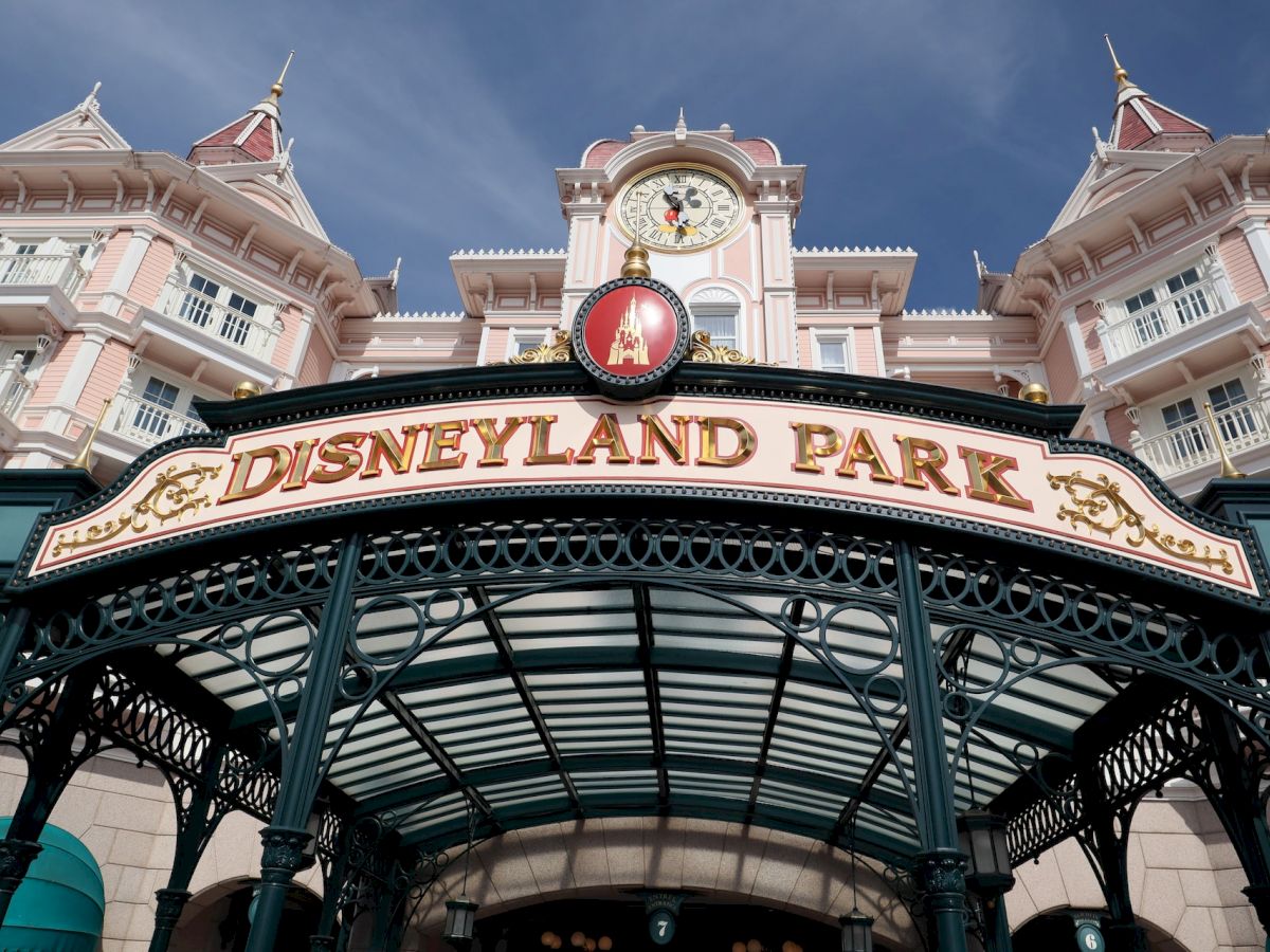 The image shows the entrance of Disneyland Park with a grand architectural style, a clock, and the distinctive 