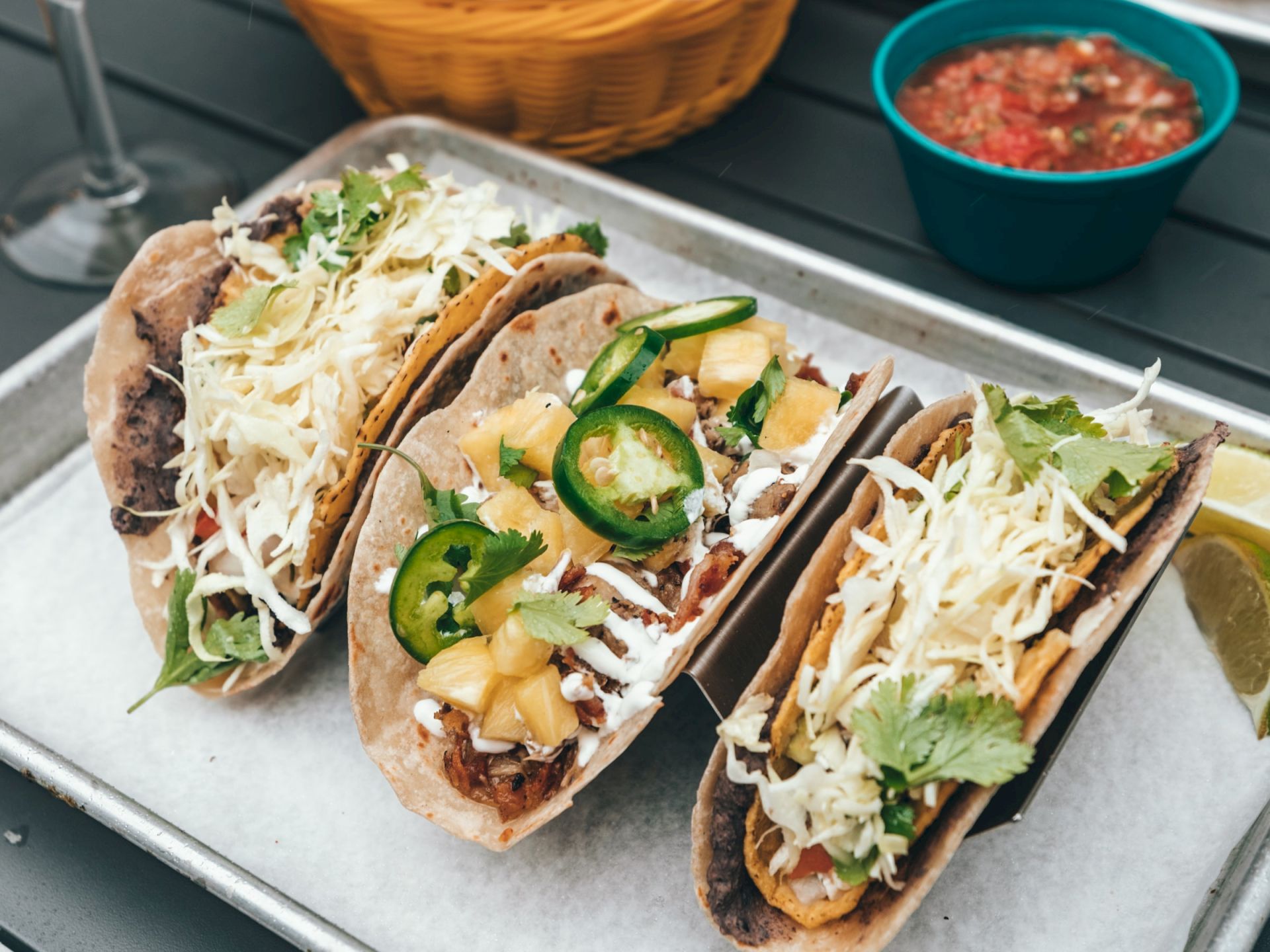 a tray of three tacos with salsa and cheese