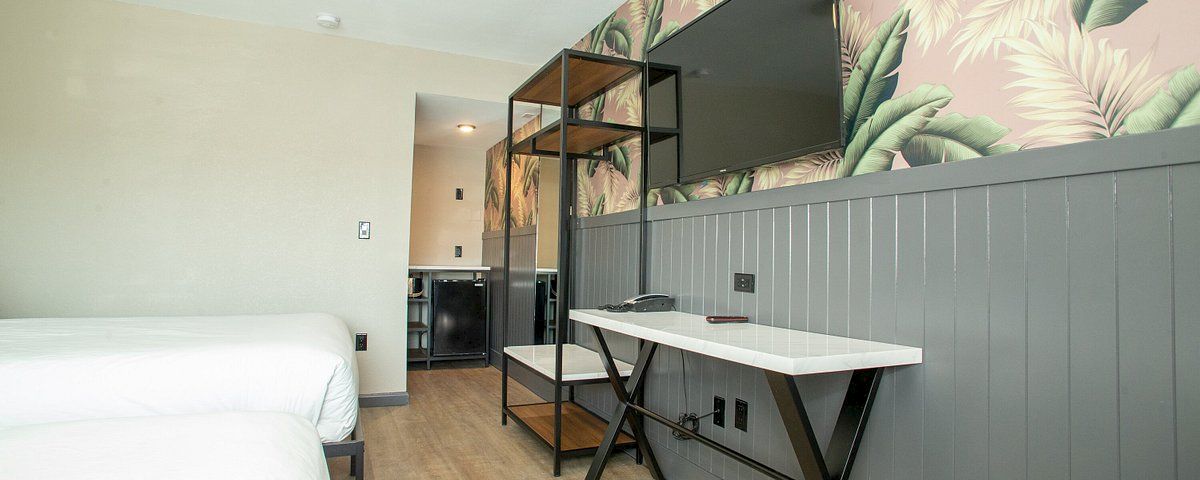 A hotel room with a bed, desk, TV, and closet organizer.