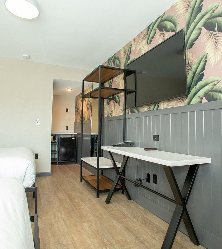 A hotel room with a desk, TV, and bed