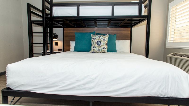 A family suite room with a bunk bed, teal pillows, and white bedding.