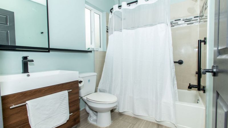 A clean bathroom with a toilet, sink, and bathtub with a shower curtain.