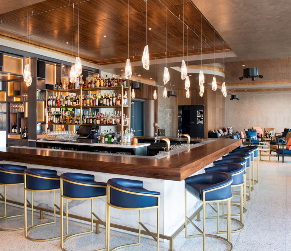A bar with a long counter and several blue stools