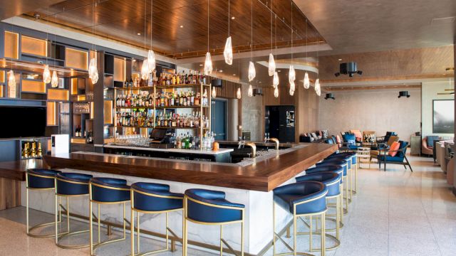 A bar with blue stools and a large selection of liquor