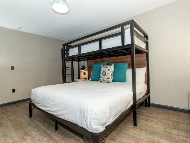 A guest room with a bunk bed, white bedding, and teal pillows.