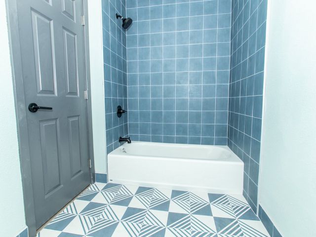 A bathroom with blue tiled walls and a white bathtub