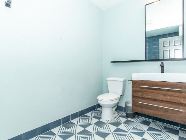 A bathroom with a toilet, sink, and mirror