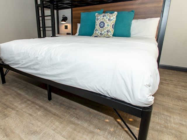 A close-up view of a bed with white sheets and teal pillows.