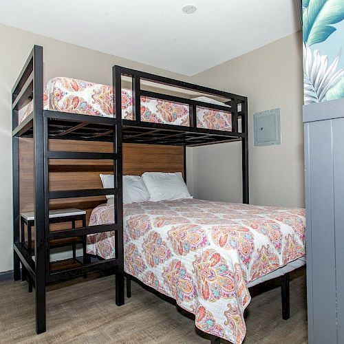 The image shows a room with a bunk bed featuring a double bed on the bottom and a single bed on top, both with floral bedding.