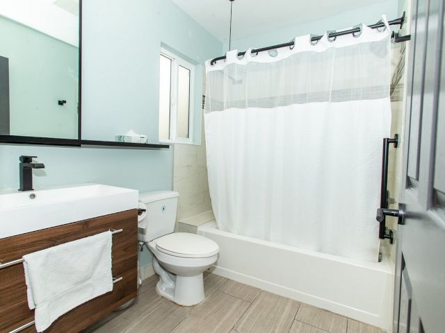 A clean bathroom with a toilet, shower, sink, and mirror.