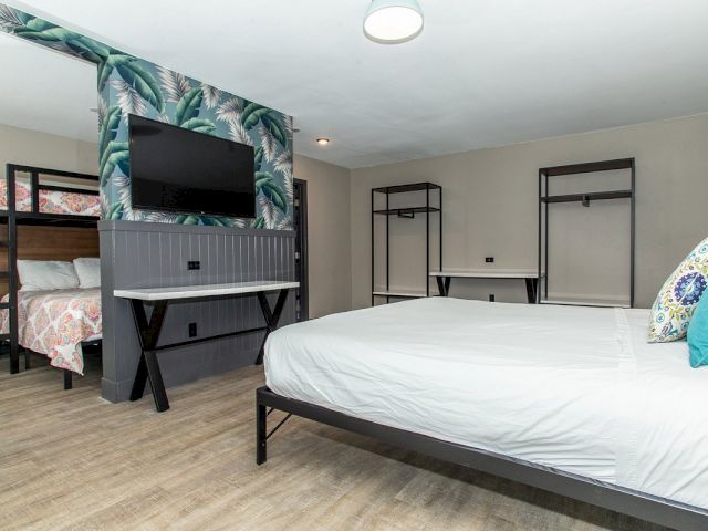 A hotel room with a large bed, bunk beds, and a TV on the wall.