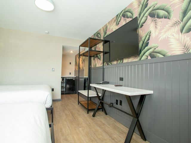 A hotel room with a bed, desk, and TV.