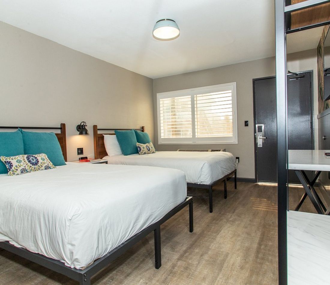 A hotel room with two beds, a desk, and a window