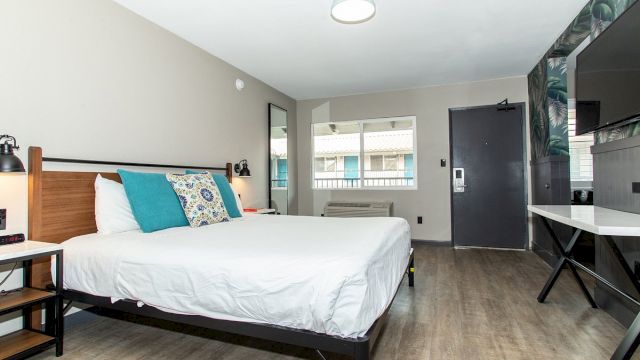 A hotel room with a bed, TV, desk, and window.